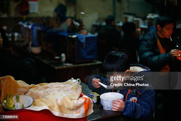 Child has breakfast at a Laohuzao teahouse at an alleyway January 23, 2007 in Shanghai, China. Laohuzao is a traditional store which sells hot water...