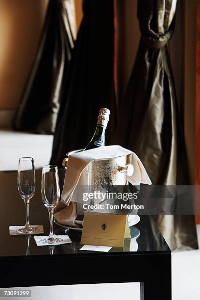 champagne glasses beside bottle in ice bucket on table - ice bucket stock-fotos und bilder