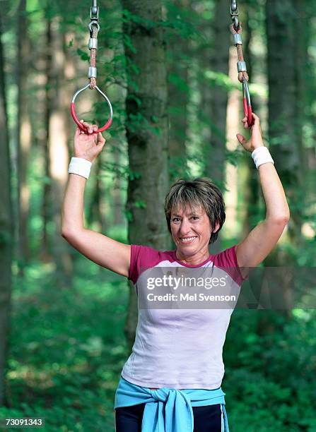 woman holding gymnastic rings in forest, portrait - ringen stock-fotos und bilder