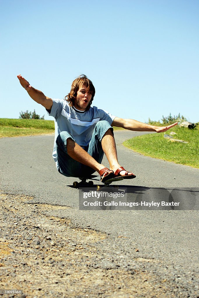 Young man with arms outstretched on skateboard