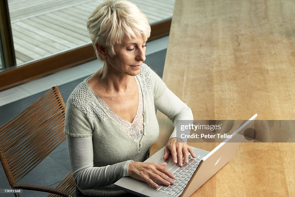 Senior woman sitting at desk using laptop