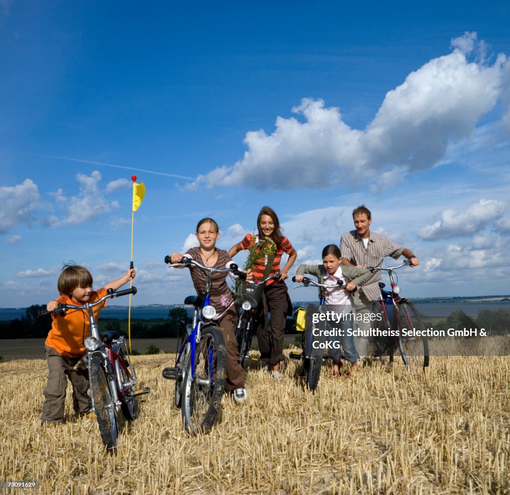 Parents with three children (6-11) standing at bicycles on grass