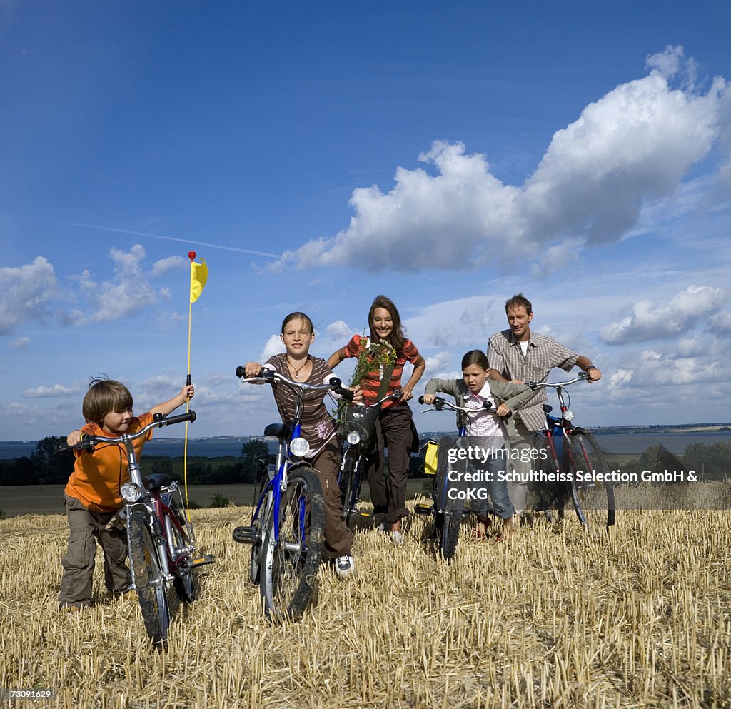 Parents with three children (6-11) standing at bicycles on grass