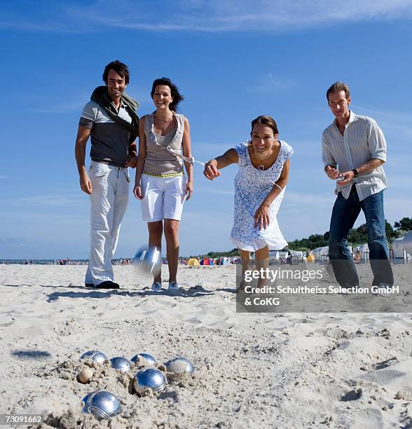 two couples playing boules on beach - group h photos et images de collection