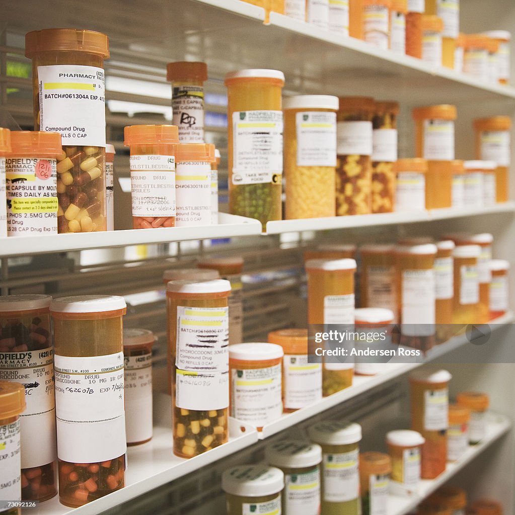 Rows of pill bottles on shelves in pharmacy, differential focus