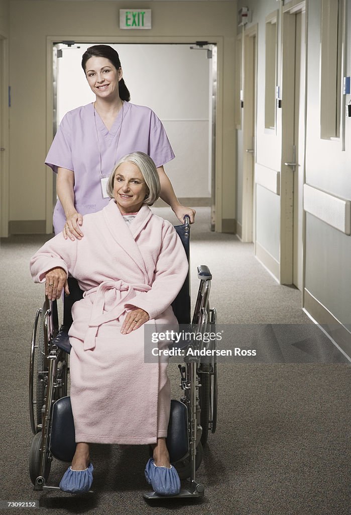 Female nurse pushing senior female patient in wheelchair, portrait