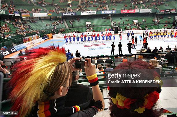 German spectator wearing a wig in the German national colors takes a picture ahead of the match Slovenia vs Germany, 24 January 2007 in the Gerry...