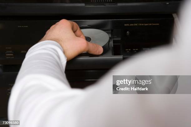 man inserting disk into dvd player - dvd player stock pictures, royalty-free photos & images