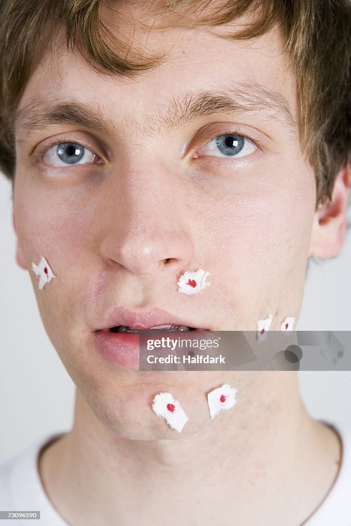 Young man with tissue paper on shaving wounds