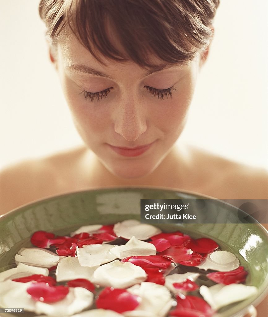 Woman holding a bowl of water with rose petals