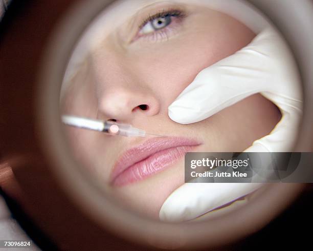 reflection in mirror of surgeon giving woman a neurotoxin injection injection - painful lips stock pictures, royalty-free photos & images