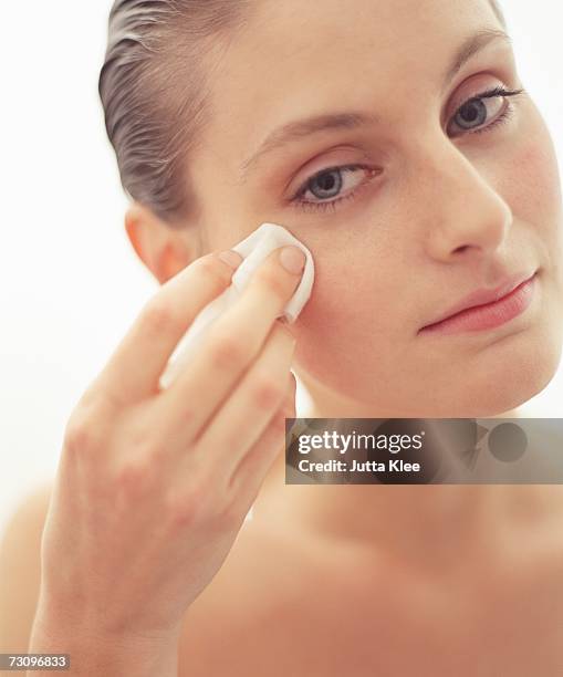 young woman holding tissue on cheek - make up verwijderen stockfoto's en -beelden