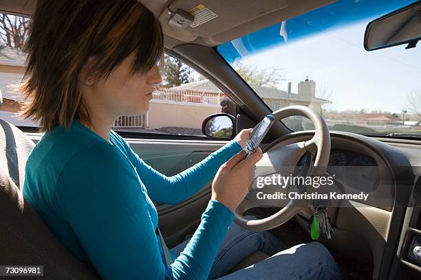 young woman sitting in driver?s seat of a car and looking at mobile phone - driver's seat ストックフォトと画像