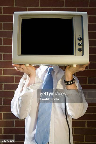 man holding a television in front of his face - satire stock-fotos und bilder