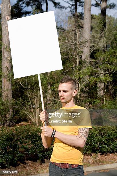 man standing on a roadside holding a blank placard - man placard stock pictures, royalty-free photos & images