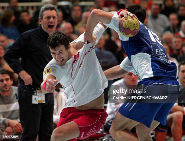 Poland's Marcin Lijewski attempts to get past France's Nikola Karabatic while his trainer Claude Onesta looks on during their main round match of the...