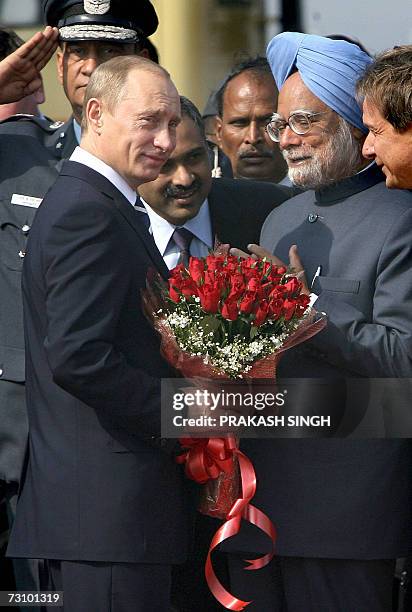 Indian Prime Minister Manmohan Singh welcomes Russian President Vladimir Putin with a flower bouquet upon arrival at Air Force station in New Delhi,...