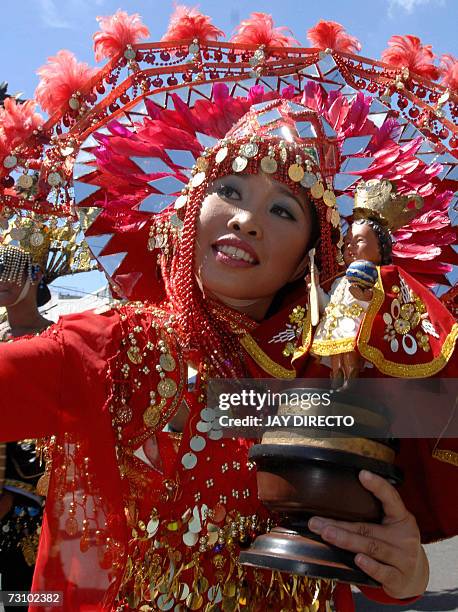 Performers dancing in the street holding a religious icon of the Santo Nino, during the culmination of the nine-day religious festival called...