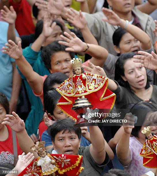 Devotees, attending a mass, raise their hands in prayer as they hold a religious icon of the Santo Nino, at the Basilica Del Santo Nino in Cebu city,...