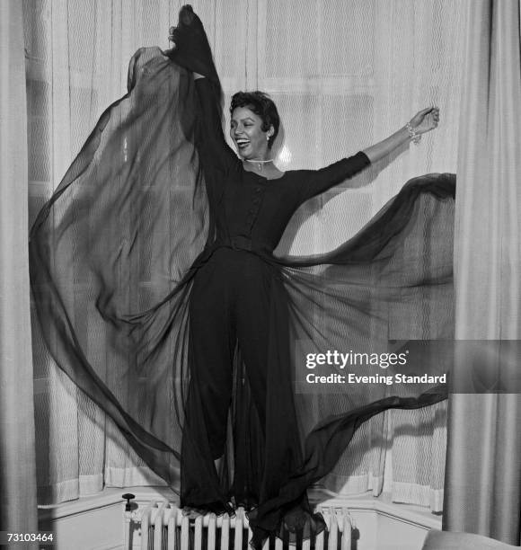 American actor and singer Dorothy Dandridge strikes a pose standing on a radiator in a bay window, 26th April 1956.