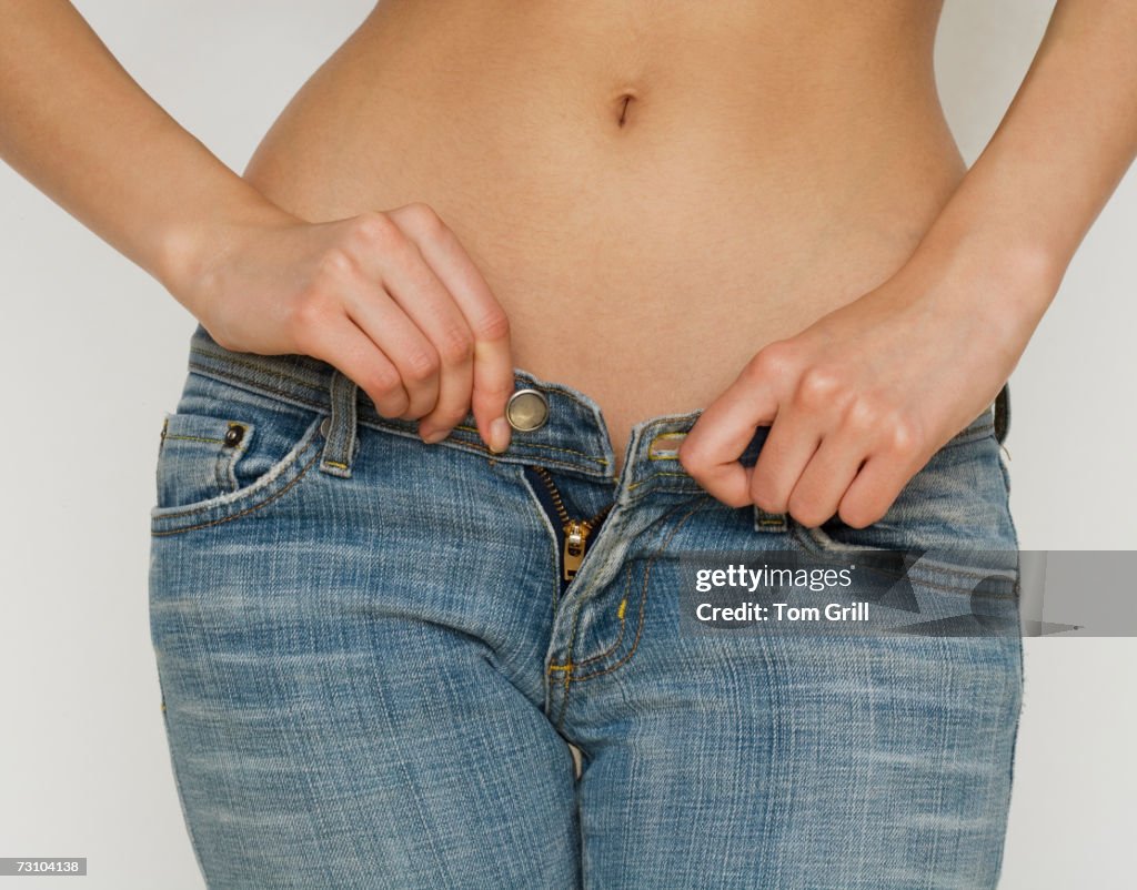 Woman buttoning jeans