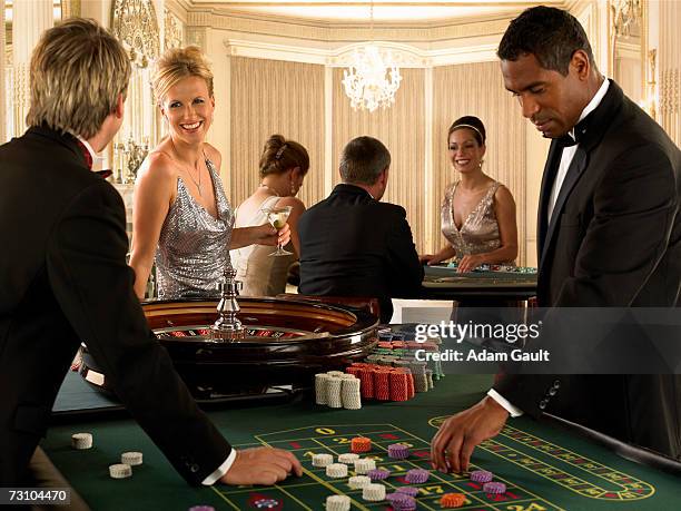 group of friends playing at roulette table in casino - roulette table ストックフォトと画像