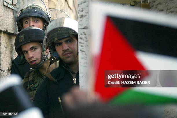 Israeli soldiers look on from their barricade as Palestinian citizens a fix their national flags to the fencing of their checkpoint placed in the...