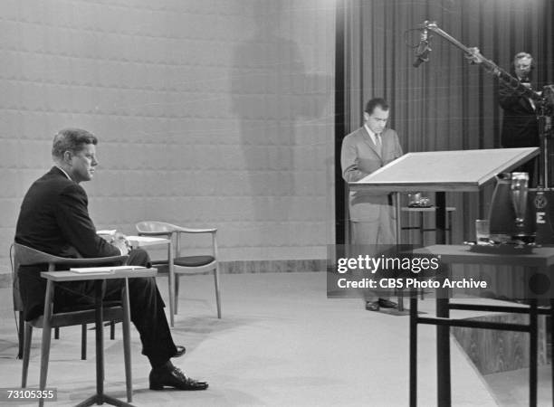 American then-senator and future President John F. Kennedy sits at left and then-Vice President and future President Richard Nixon stands, as both...