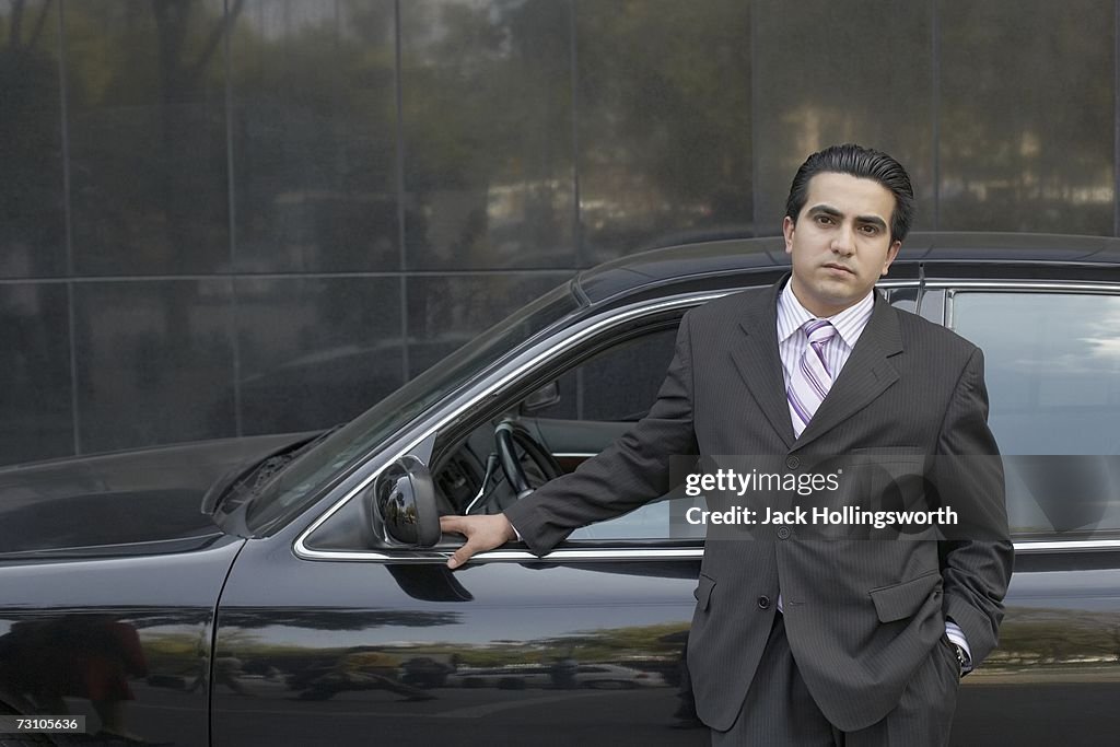Portrait of a businessman standing beside a car