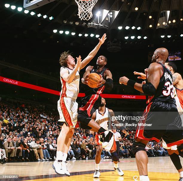 Dwyane Wade of the Miami Heat takes the ball to the basket against Troy Murphy of the Golden State Warriors during a game at Oracle Arena on January...