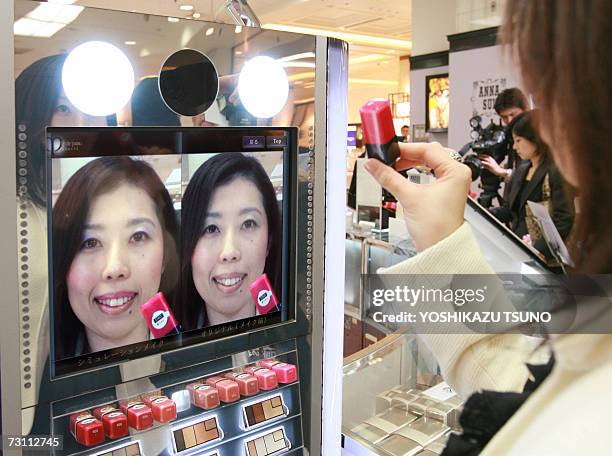 Sales clerk of Tokyo's Mitsukoshi department store demonstrates a virtual make-up system which enables it sto display before and after make-up face...