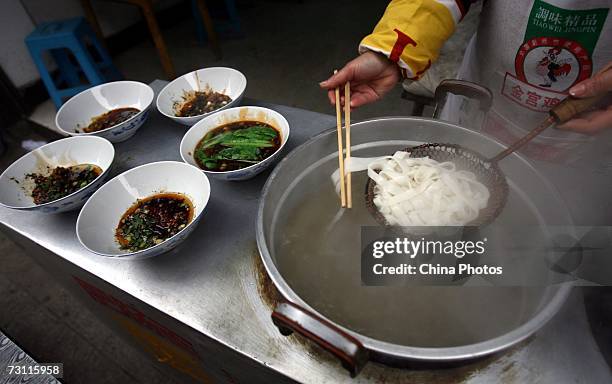 Cook boils rice noodles at a noodle workshop in Wansheng District on January 25, 2007 in Chongqing Municipality, China. Rice noodles are made from...