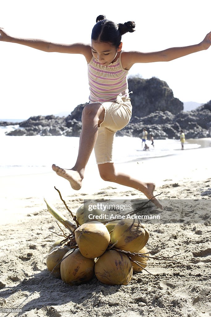 Young girl (8-9) jumping over coconuts