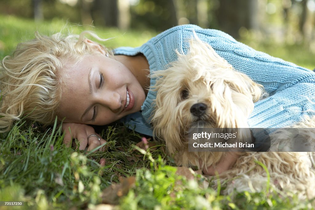 Young woman lying on grass with dog