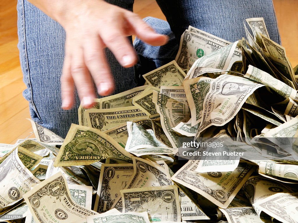 Woman reaching for pile of US banknotes