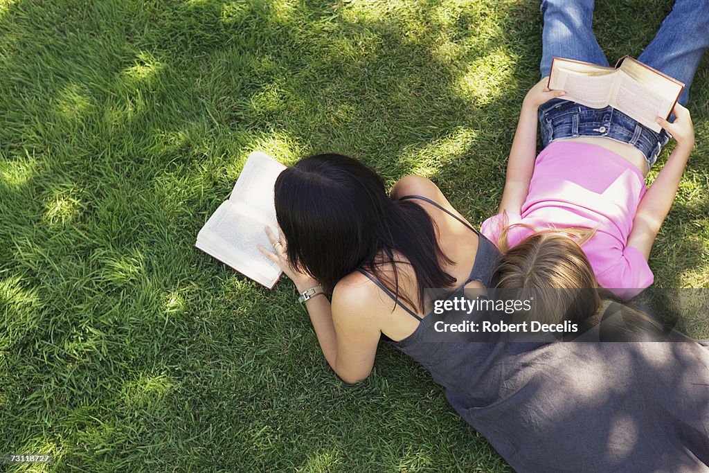 Mother and daughter (8-9) reading on grass, elevated view