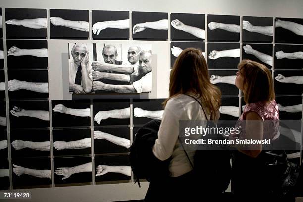 People look at photos of Holocaust survivors displaying their identification tattoos at the US Holocaust Memorial Museum January 26, 2007 in...
