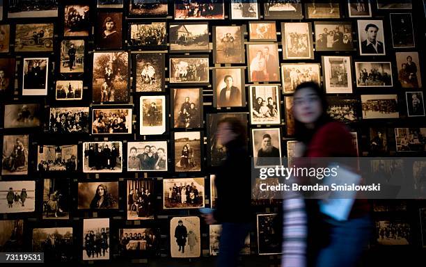 People walk past a wall of photos from the town of Eishishok, located in Lithuania, where the Nazis first began to implement the "Final Solution" at...