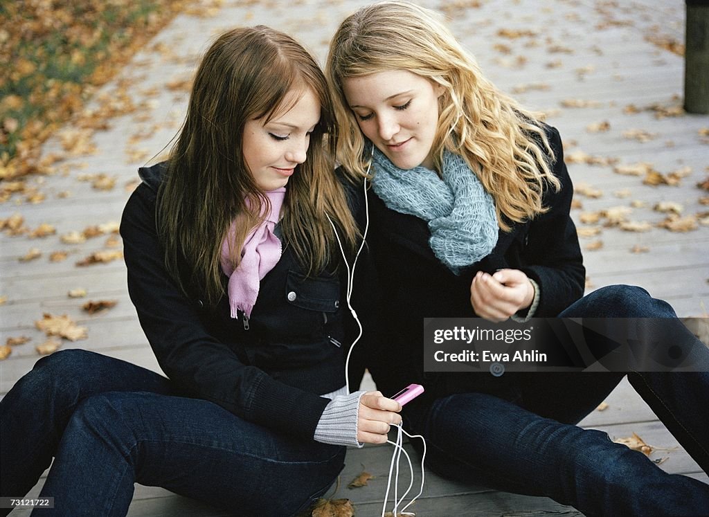 Two teenage girls listening to music.