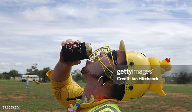 Chad Rosenblatt of the team 'Outcasts' wears a punishment helmet after he got out for a duck but is still able to drink a beer during the Goldfield...