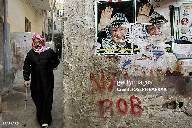 Palestinian elderly man walks near a wall adorned with posters of late Palestinian leader Yasser Arafat in the Palestinian refugee camp of Burj...