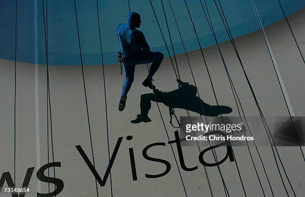 Member of the "GROUNDED Aerial Dance Theater" hang from ropes and dance on a poster promoting Vista, a new version of Microsoft Windows, on the side...
