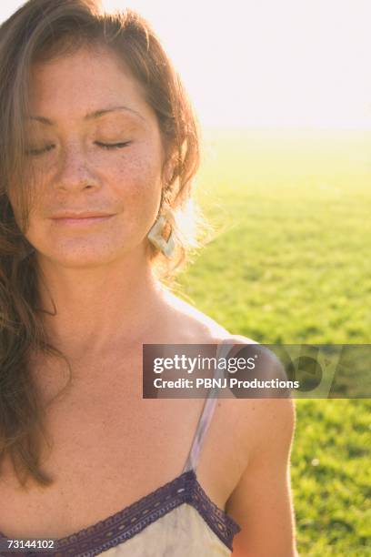 woman with eyes closed in sunlit meadow - destiny stockfoto's en -beelden