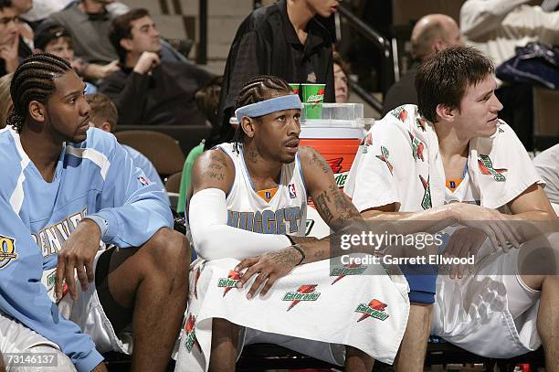 Allen Iverson of the Denver Nuggets sits on the bench between Nene and Eduardo Najera during the NBA game against the Boston Celtics on December 26,...