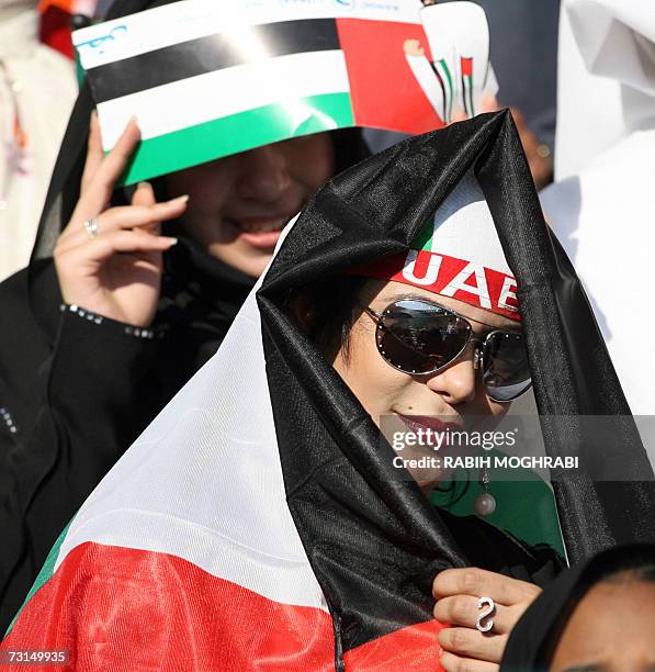 Abu Dhabi, UNITED ARAB EMIRATES: A supporter of the Emirati football team raps the national flag around her head ahead of the final Gulf Cup match...