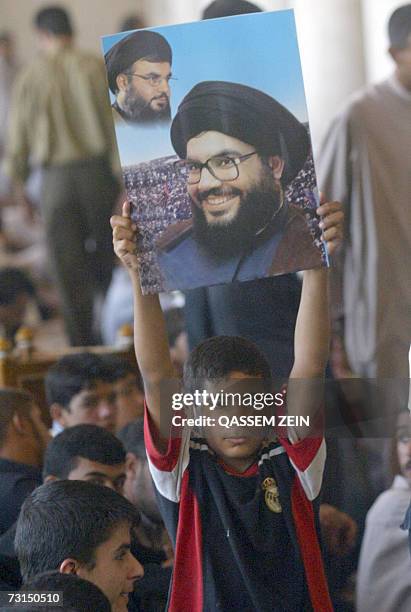 Young Iraqi boy flashes a poster of Lebanese Hezbollah leader Sheikh Hassan Nasrallah as he stands among supporters of radical Shiite cleric Moqtada...