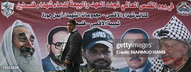 Palestinian man walks past a large banner of late Palestinian leaders from left to right, the spiritual leader of Hamas Sheikh Ahmed Yassin...