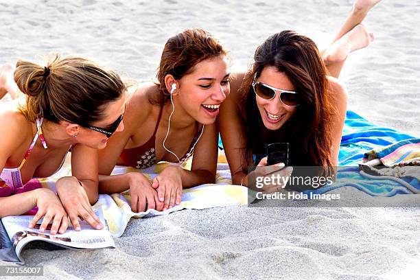 young women reading magazines and sunbathing on beach - american sunbathing association photos et images de collection