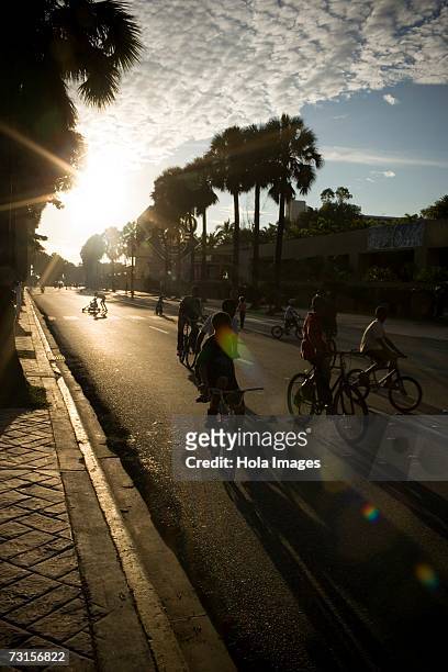 silhouette of a group of people riding bicycles, malecon, santo domingo, dominican republic - malecon stock-fotos und bilder