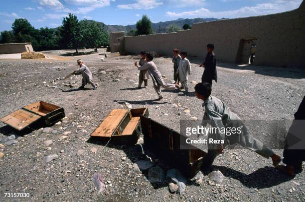 Children play cricket in the middle of empty munitions boxes in the Pashtun tribale zone, next to Parachinar in a Shiite village on July, 2004 in...